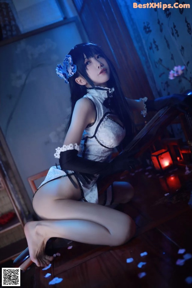 A woman in a white and black outfit sitting on a wooden floor.