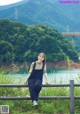 A woman sitting on a fence in front of a river.
