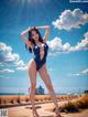 A woman in a blue bathing suit standing on a beach.