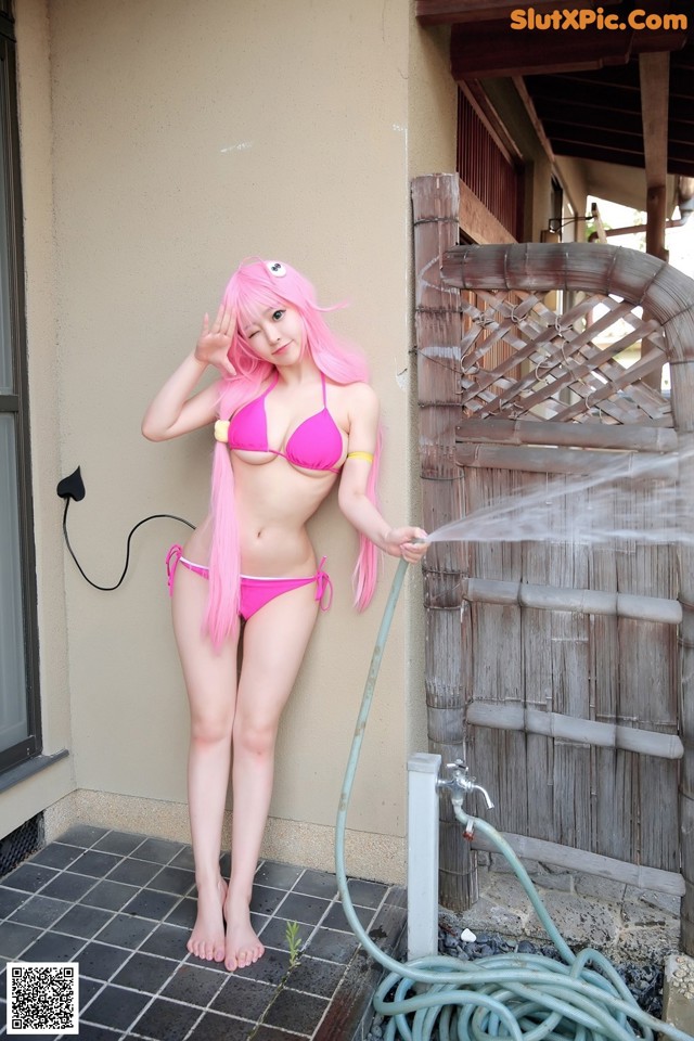 A woman in a pink bikini standing next to a hose.