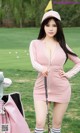 A woman in a pink dress holding a golf club.