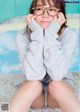 A young woman wearing glasses sitting on the floor.