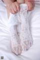 A woman is putting on a pair of white lace socks.