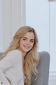 A woman sitting on a gray chair smiling at the camera.