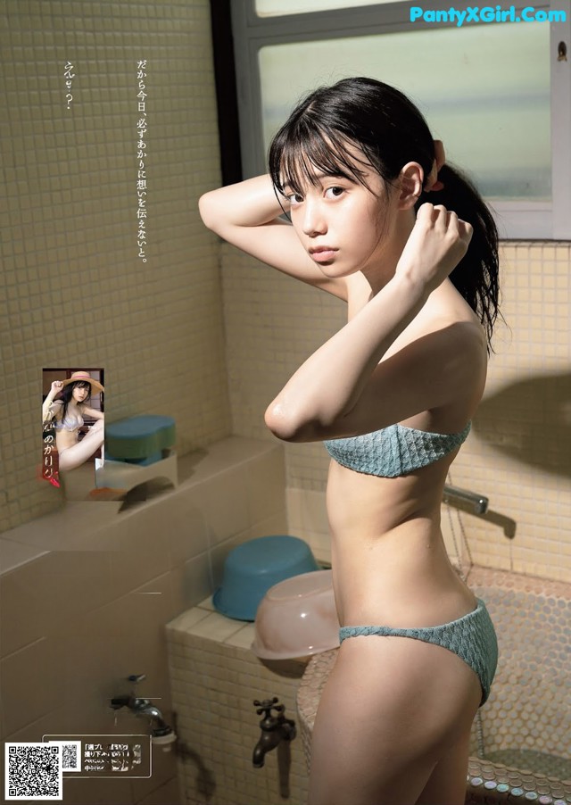 A woman in a blue bikini standing in a bathroom.