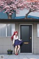 A girl standing in front of a house with a tree in the background.